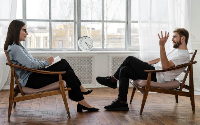 A therapist engaging in a counseling session with a male patient to support mental health.